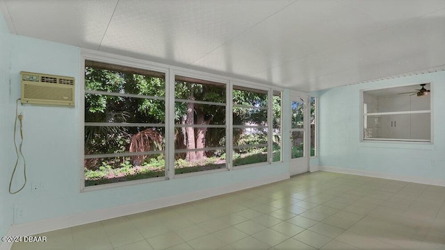 unfurnished sunroom with an AC wall unit and ceiling fan