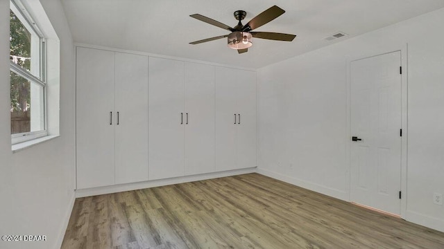 unfurnished bedroom featuring ceiling fan, light hardwood / wood-style flooring, and multiple windows