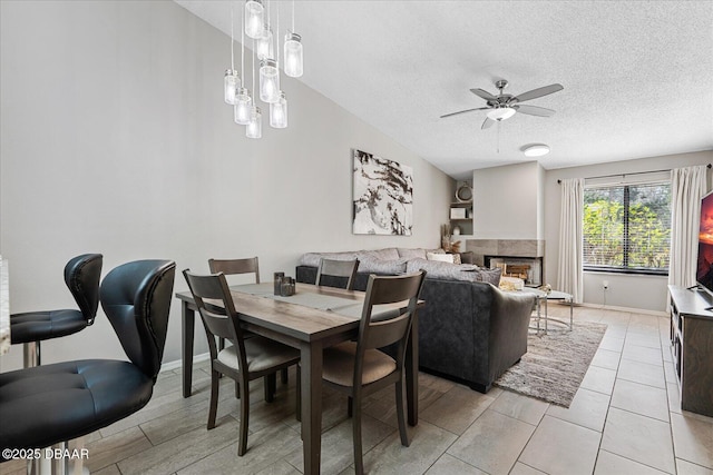 dining space featuring a multi sided fireplace, ceiling fan, and a textured ceiling