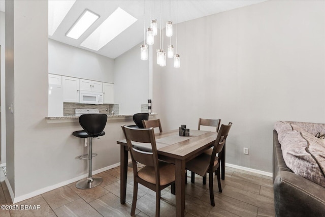 dining area featuring wood-type flooring, high vaulted ceiling, and a skylight