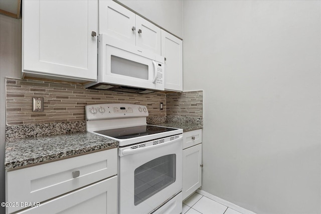 kitchen with tasteful backsplash, dark stone countertops, white cabinets, light tile patterned floors, and white appliances