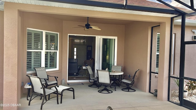 view of patio featuring outdoor dining space, ceiling fan, and a lanai