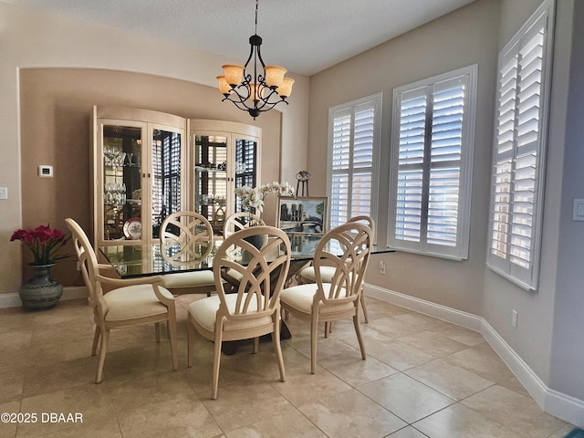 dining area featuring light tile patterned floors, a textured ceiling, an inviting chandelier, and baseboards