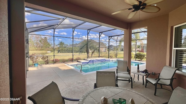 outdoor pool featuring glass enclosure, a ceiling fan, a patio area, and a hot tub