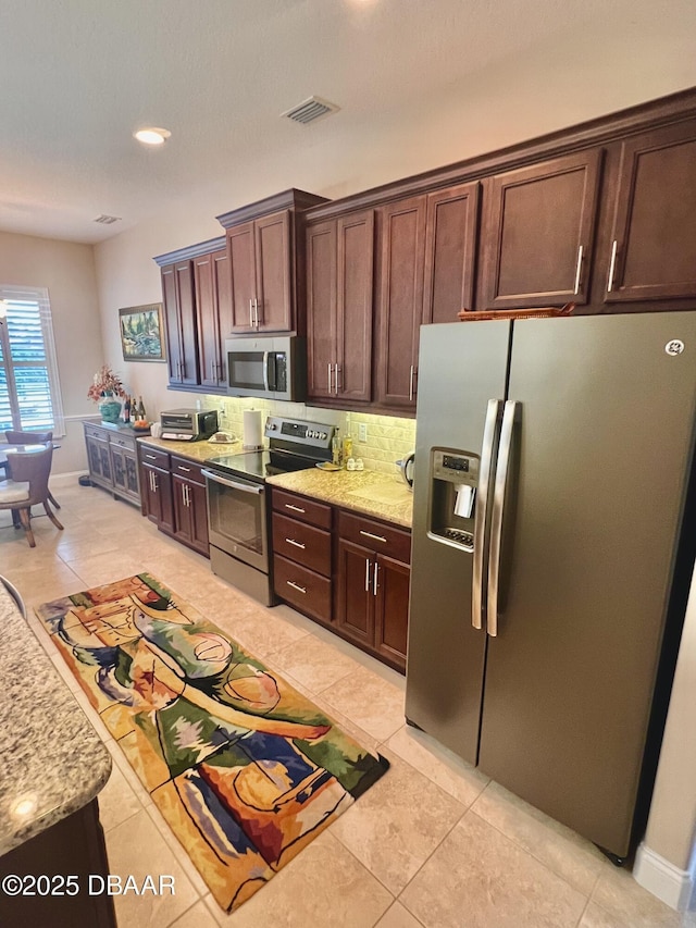 kitchen featuring light stone countertops, visible vents, light tile patterned flooring, and stainless steel appliances