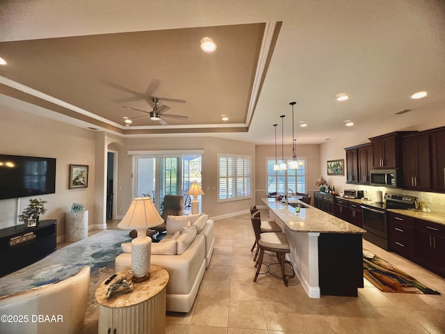 kitchen with a sink, hanging light fixtures, an island with sink, stainless steel appliances, and a breakfast bar