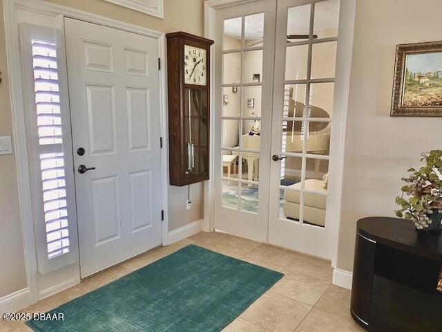 entryway with baseboards, light tile patterned flooring, and plenty of natural light