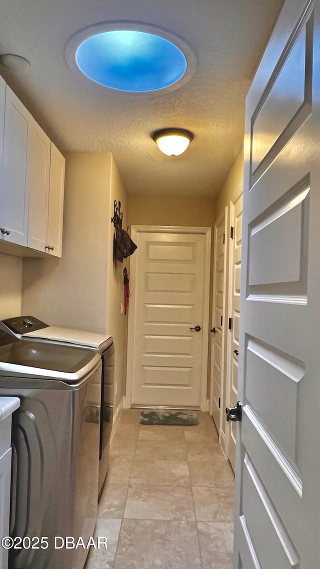 clothes washing area with washing machine and dryer, cabinet space, and a textured ceiling