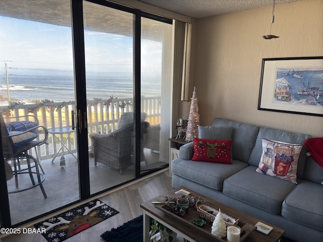 living room featuring a textured ceiling, wood-type flooring, a healthy amount of sunlight, and a water view