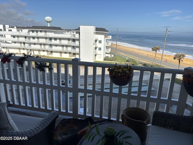 balcony with a water view and a view of the beach