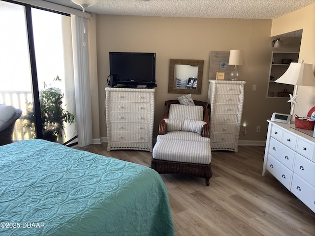 bedroom with wood-type flooring, a textured ceiling, and a baseboard heating unit