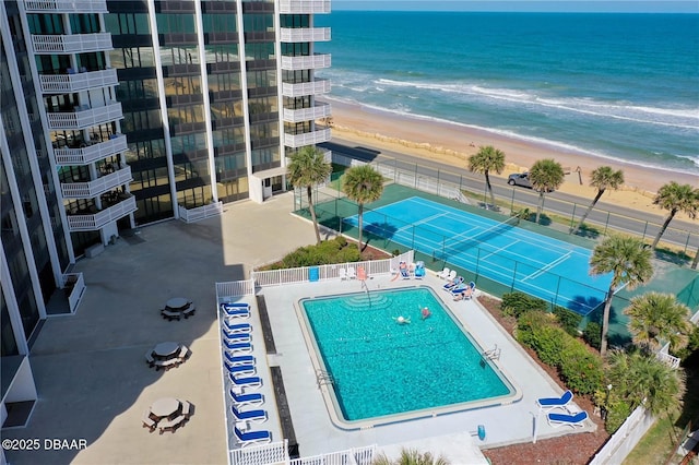 view of pool featuring a view of the beach, a patio area, and a water view