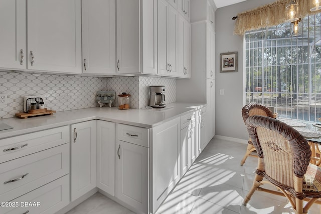 kitchen with white cabinetry, backsplash, and light tile patterned flooring