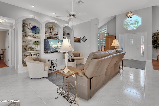 living room featuring light tile patterned floors, built in shelves, and ceiling fan