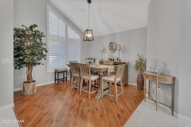 dining space with an inviting chandelier, vaulted ceiling, and light hardwood / wood-style flooring