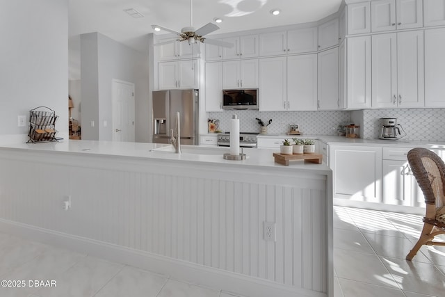 kitchen with tasteful backsplash, stainless steel appliances, white cabinets, and light tile patterned flooring