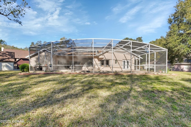 back of property with a yard, glass enclosure, and a patio area