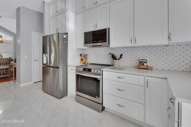 kitchen with white cabinetry, stainless steel appliances, decorative backsplash, and light tile patterned floors