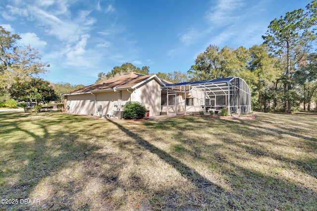 rear view of property featuring a yard and glass enclosure