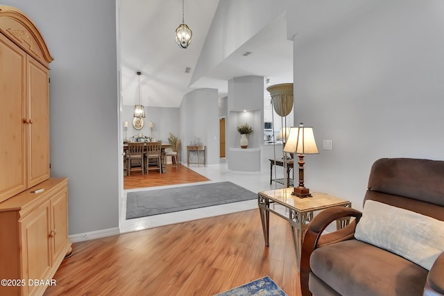 living area featuring high vaulted ceiling, a chandelier, and light hardwood / wood-style floors