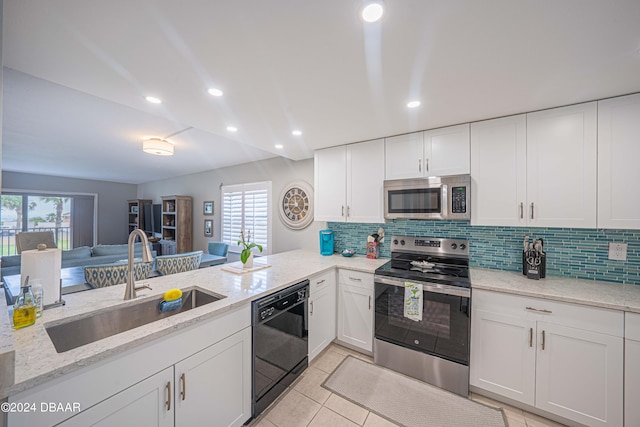 kitchen with kitchen peninsula, appliances with stainless steel finishes, light stone counters, and a healthy amount of sunlight