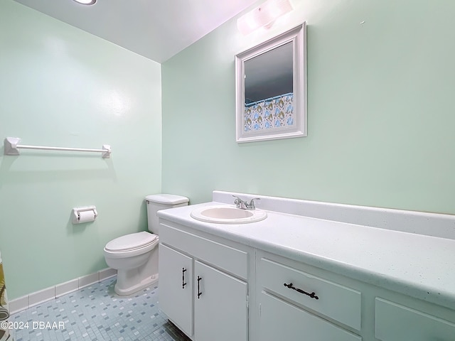 bathroom with toilet, vanity, and tile patterned floors