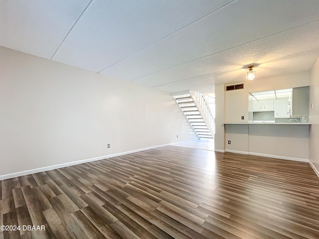 unfurnished living room featuring a textured ceiling and dark hardwood / wood-style floors