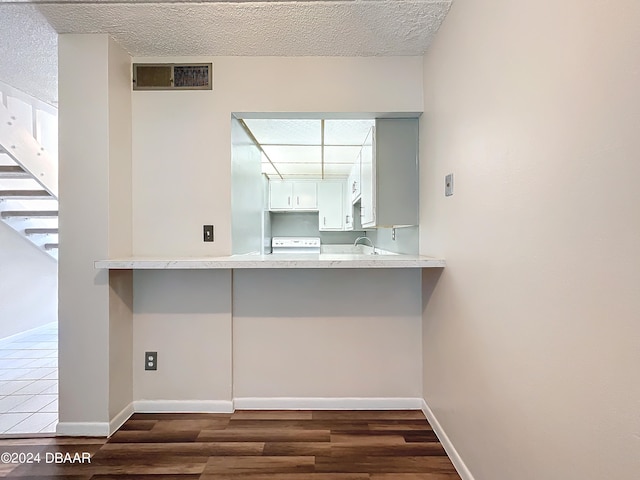 kitchen featuring a textured ceiling, range, dark hardwood / wood-style floors, sink, and white cabinets