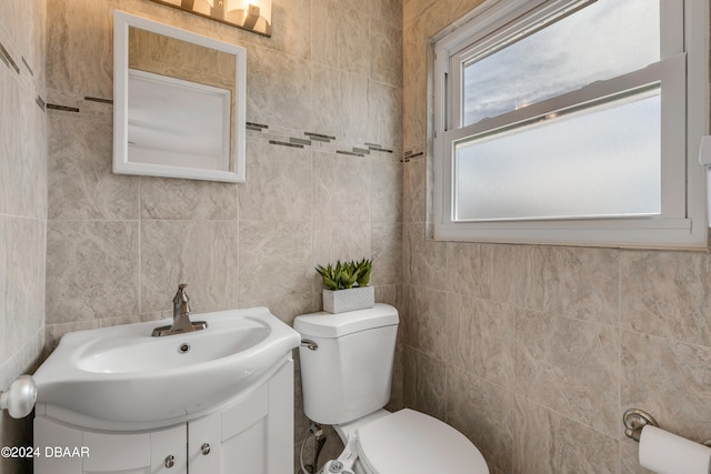 bathroom with tile walls, vanity, a healthy amount of sunlight, and toilet