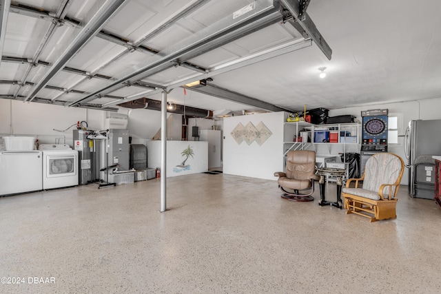 garage featuring electric water heater, stainless steel fridge, and washer and clothes dryer