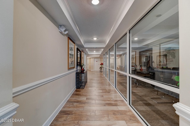 hallway with a textured ceiling, crown molding, light hardwood / wood-style floors, and a raised ceiling