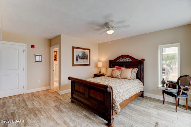 bedroom with ceiling fan, ensuite bath, and light wood-type flooring