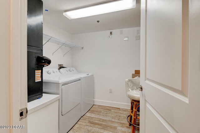 washroom featuring washing machine and clothes dryer and light hardwood / wood-style flooring