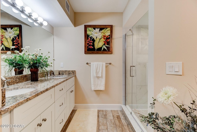 bathroom with a shower with shower door and vanity