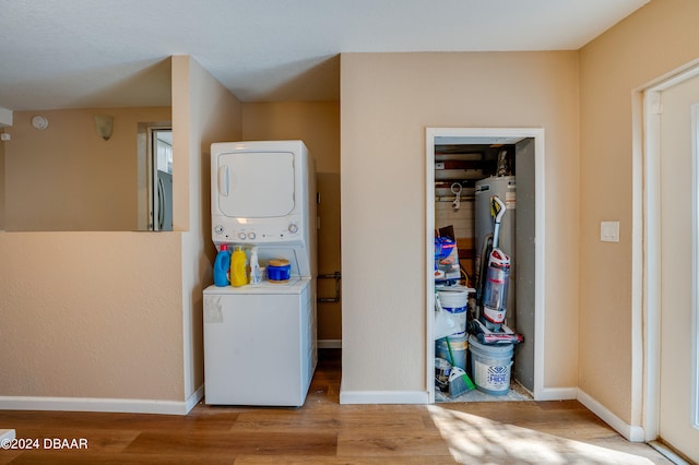 laundry area with stacked washer / dryer and light wood-type flooring