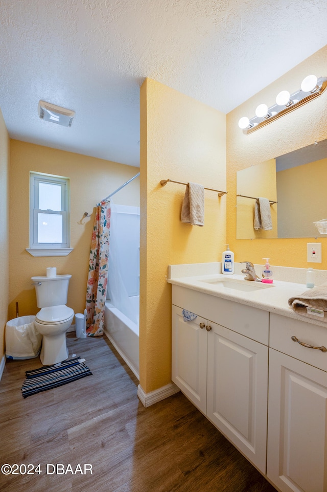 full bathroom featuring hardwood / wood-style floors, vanity, and a textured ceiling