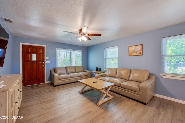 living room with ceiling fan, a textured ceiling, and light wood-type flooring