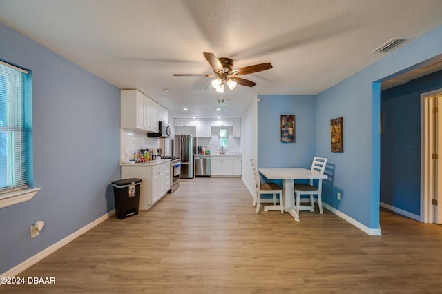 kitchen featuring light hardwood / wood-style flooring, decorative backsplash, stainless steel appliances, and white cabinets