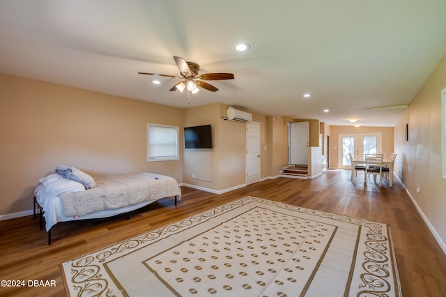 bedroom featuring hardwood / wood-style floors, a wall mounted air conditioner, and ceiling fan