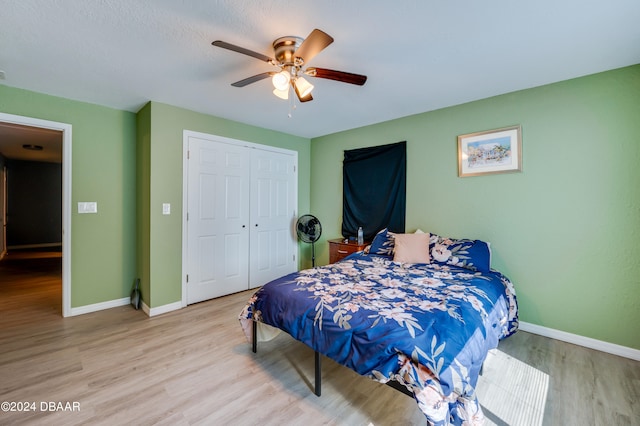 bedroom with light hardwood / wood-style flooring, ceiling fan, and a closet