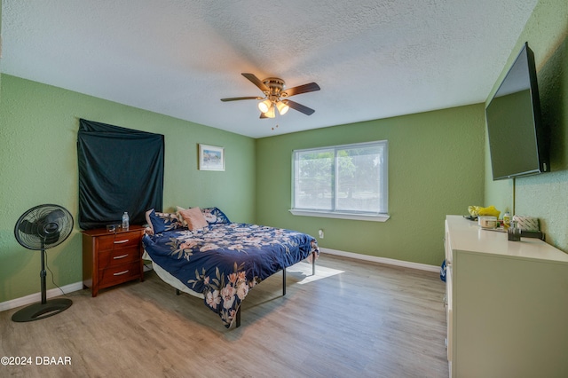 bedroom featuring a textured ceiling, light hardwood / wood-style flooring, and ceiling fan