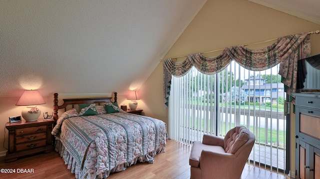 bedroom featuring access to exterior, light hardwood / wood-style flooring, and lofted ceiling