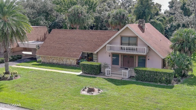 view of front of house with a fire pit, a front lawn, and a balcony