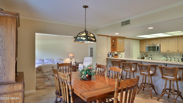 dining area featuring a textured ceiling, light tile patterned floors, crown molding, and sink