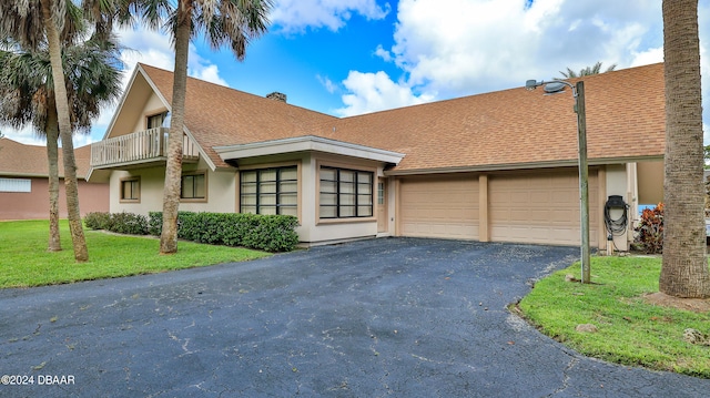 view of front of property featuring a balcony, a front yard, and a garage