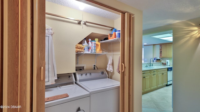 clothes washing area featuring a textured ceiling, separate washer and dryer, and sink