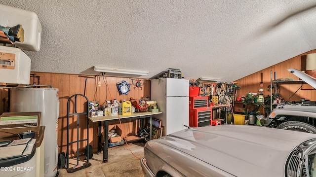 garage with wood walls, white fridge, and electric water heater