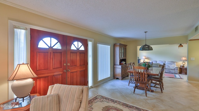 tiled foyer featuring a textured ceiling and ornamental molding