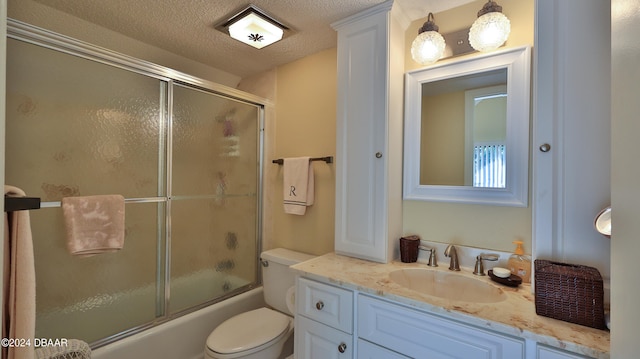 full bathroom with toilet, vanity, a textured ceiling, and combined bath / shower with glass door