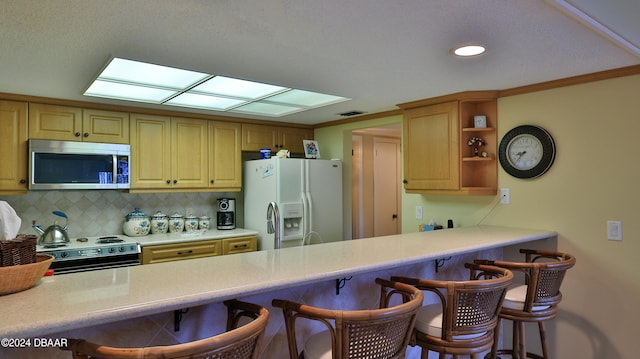 kitchen with electric range oven, tasteful backsplash, a breakfast bar, and white refrigerator with ice dispenser